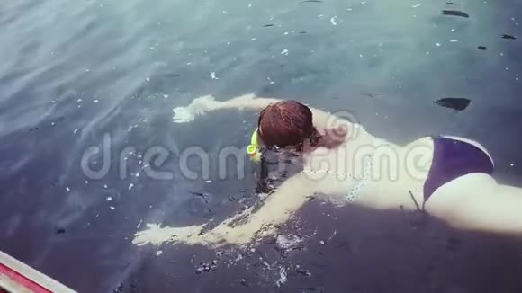 穿比基尼的年轻女人在面具上浮潜在海里喂鱼慢动作1920x1080视频的预览图