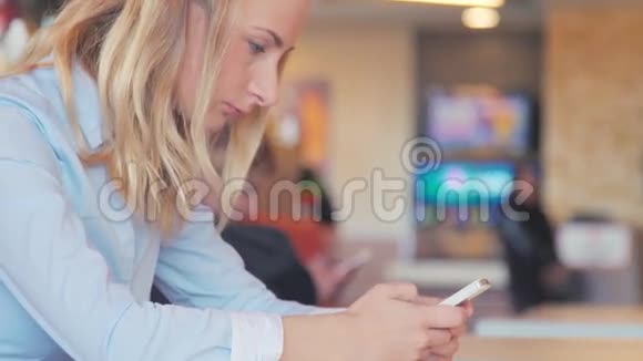 快乐的年轻女人坐在一张桌子上用手机喝咖啡视频的预览图