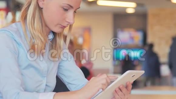 在咖啡馆工作年轻漂亮的长发女人坐在桌子旁用平板电脑视频的预览图