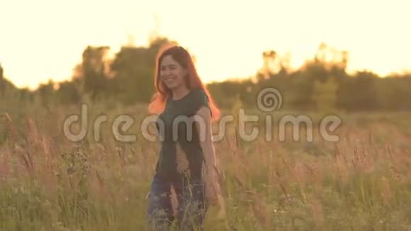 阳光明媚的年轻女子在夕阳下的田野里旋转视频的预览图