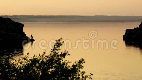 日落时分在河岸钓鱼的渔夫剪影视频的预览图