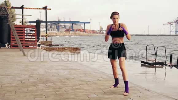 运动的年轻女子在海边玩影子拳击早上在海滩上训练漂亮的女拳击手投掷视频的预览图