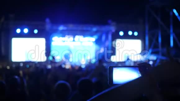 人们在摇滚音乐会上挥舞双手粉丝记录视频并在android上拍照在音乐会上视频的预览图
