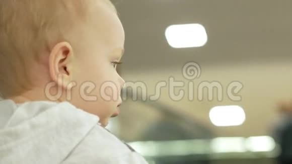 一个可爱的金发男孩和他的母亲在一个大型购物中心爬上扶梯孩子四处张望视频的预览图