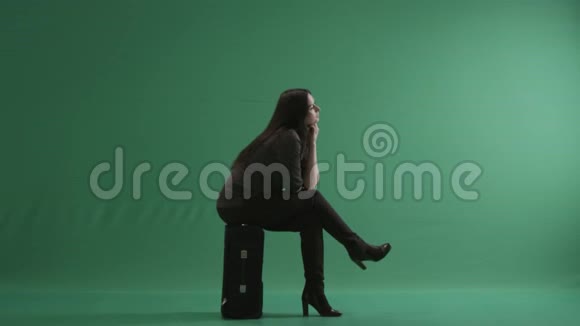 坐在行李箱上双腿交叉的女人视频的预览图