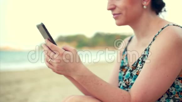 年轻快乐的高加索女人在海边使用智能手机视频的预览图