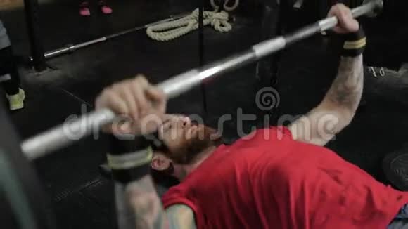 在交叉健身中心用杠铃做蹲式运动的一名集中蓄胡须的运动男子的肖像视频的预览图