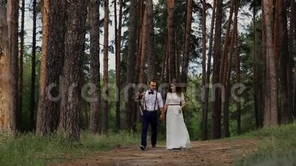 在针叶林中散步的美丽幸福夫妇在一条林间小路上拍照互相沟通视频的预览图