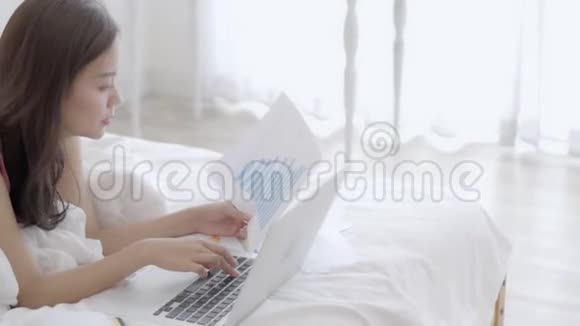 漂亮的亚洲年轻女性在办公室用手提电脑打字女商人看图分析视频的预览图