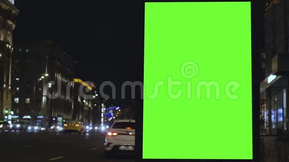 有绿色屏幕的广告牌位于一条繁忙的街道上汽车在晚上移动视频的预览图