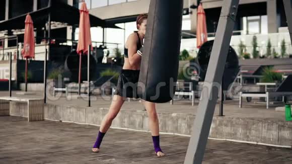 强壮的女拳击手戴手套带着一个袋子锻炼在外面健身女拳击手训练自卫视频的预览图