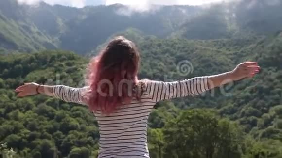 年轻美丽的女孩站在山上举起渴望飞翔视频的预览图