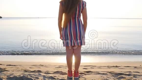 快乐的女人站在水边手臂举在沙滩上视频的预览图