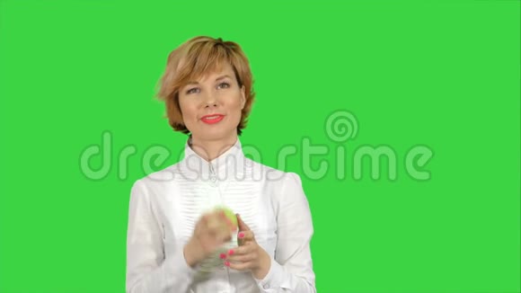 年轻女性在绿色屏幕上吃绿色苹果的肖像Chroma键视频的预览图