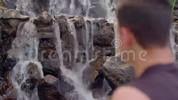 人在瀑布附近放松放松的概念头部特写视频的预览图