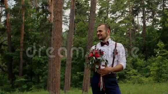 肖像婚礼新郎与手中的花束在夏季森林视频的预览图