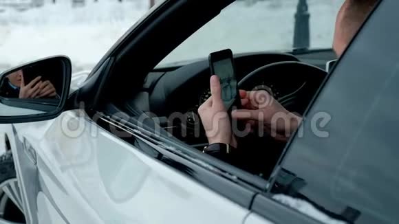 一个成功的可敬的商人在一辆昂贵的汽车的车轮上使用电话视频的预览图