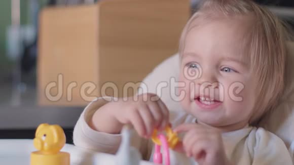可爱的小女孩坐在桌子旁玩玩具对着相机微笑视频的预览图