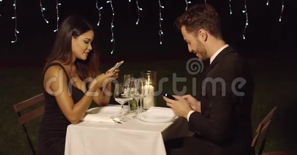 年轻夫妇在晚餐时查看手机视频的预览图
