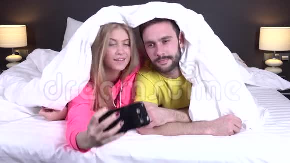 一对在舒适的床上自拍的情侣视频的预览图