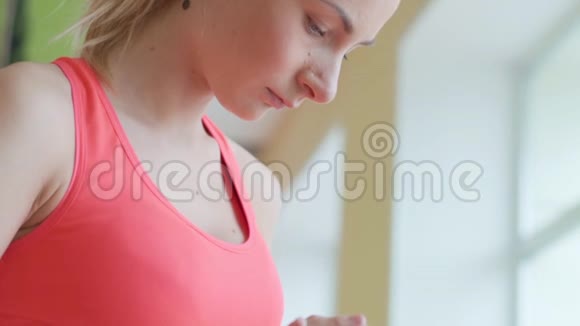 快乐可爱的年轻女运动员坐在健身房里用平板电脑视频的预览图