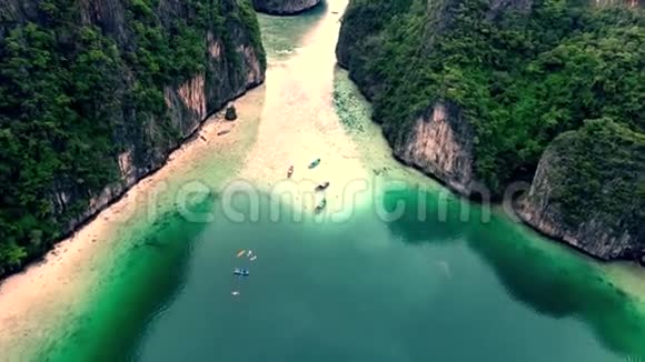 蓝绿色的小旅游船平静的海水周围环绕着巨大的热带石岩岛森林空中4k视频的预览图