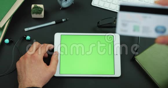 男人拿着绿色屏幕的平板电脑在带有绿色屏幕的桌子上输入信用卡信息视频的预览图