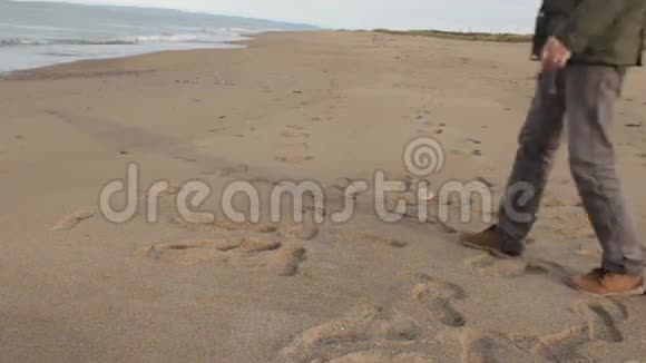 一个留着胡子的中年男子走进了相框坐在沙滩上望着远处站着视频的预览图