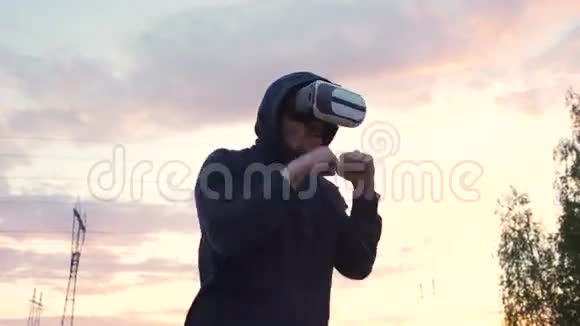 年轻男子拳击手在VR360耳机培训踢虚拟现实战斗日落在城市公园视频的预览图
