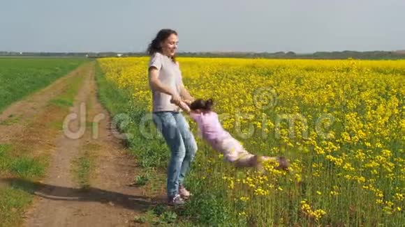那个女人正在转动婴儿妈妈和女儿在大自然中开着黄花的幸福家庭油菜田视频的预览图