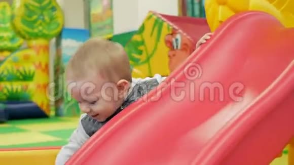 一个可爱的孩子站在游乐园的红色滑梯附近视频的预览图