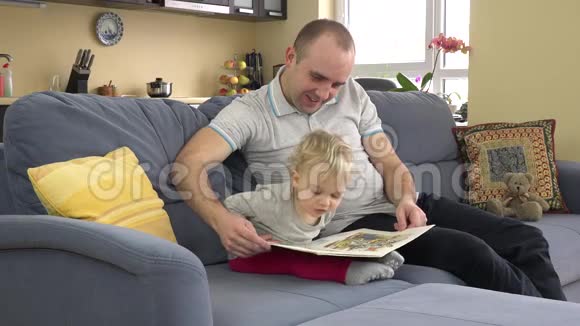 情绪化的小女孩和父亲在沙发房看书4K视频的预览图