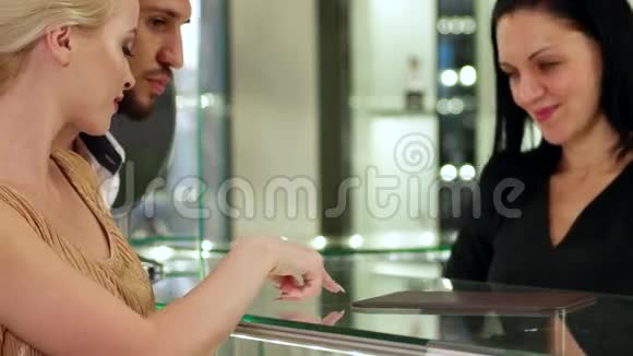 珠宝店卖家展示年轻夫妇的金戒指一对结婚戒指店面情侣在视频的预览图
