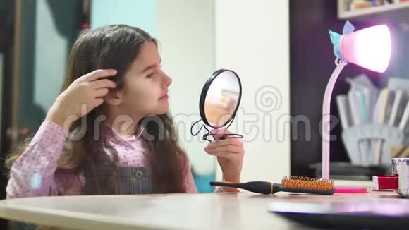 小女孩梳头做发型十几岁的女孩卷起她的梳子和室内镜子年轻少女女性视频的预览图