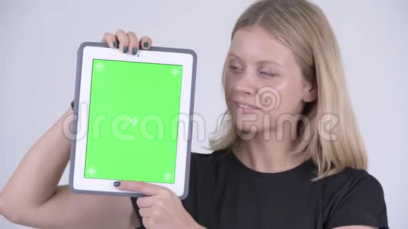 年轻快乐的金发女郎展示数码平板电脑的脸视频的预览图