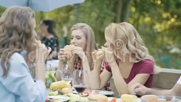 吃汉堡的朋友坐在户外聚会的餐桌上视频的预览图