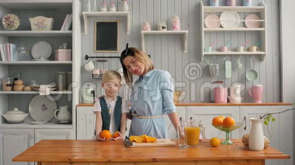 美丽幸福的妈妈带着橙汁在厨房里的孩子微笑着美国家庭早餐视频的预览图