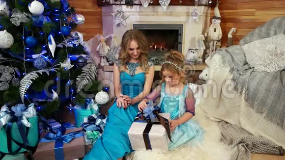 可爱的小女孩带着妈妈的容貌打开一个圣诞礼物包装精美有蝴蝶结礼物视频的预览图