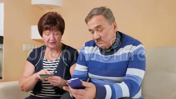 老年夫妇通过信用卡和电话在网上购物坐在家里的男人和女人的数据卡视频的预览图