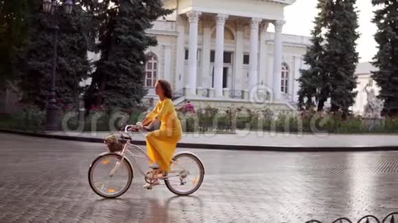 美丽的女人骑着一辆城市自行车在市中心放着篮子和鲜花早早地享受着她的时光视频的预览图