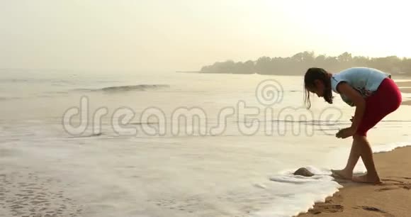 女孩独自在海滩上玩沙子视频的预览图