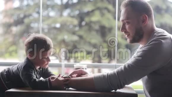 小男孩看着父亲手上的智能时钟视频的预览图