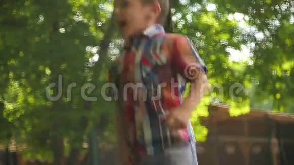 可爱的小男孩穿着格子衬衫跳在蹦床上视频的预览图
