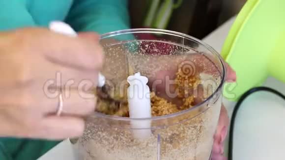 一个女人检查搅拌器碗中杏仁的研磨程度用于准备填充釉面糖果视频的预览图