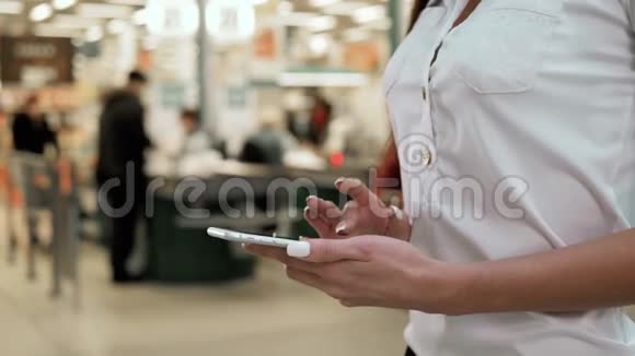 女人在超市背景下购物近距离观看女孩购买产品使用数字小工具在商店希普斯特视频的预览图