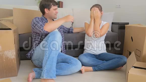 幸福的年轻夫妇坐在新家的沙发上欢呼视频的预览图