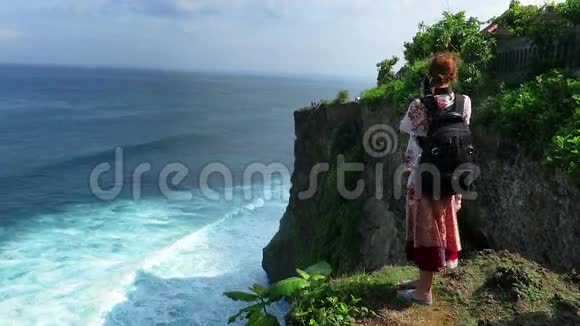 女子站在乌卢瓦图的悬崖边拍照视频的预览图