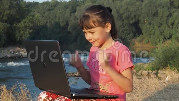 在河边拿着笔记本电脑的女孩河岸上的女孩带着笔记本电脑一个拿着笔记本电脑的小女孩视频的预览图