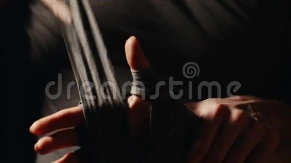 教练用绷带包扎他的手然后在一个黑色背景的杜斯科拳击手战斗准备战斗特写视频的预览图