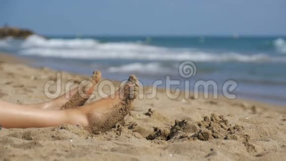 女人的腿慢慢地躺在海边的海滩上视频的预览图